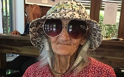 Portrait photo of Alma in large round sunglasses and a hat