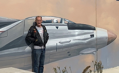 Peter Gray standing in front of a wall with a jet fighter painted on it