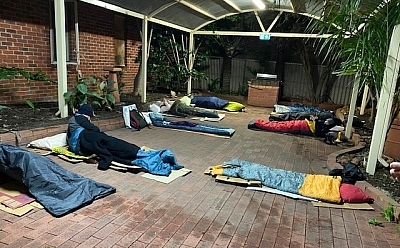 BHP staff and St Bart's executives sleep under a paved patio, rugged up in sleeping bags
