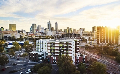 A city-scape of Perth at sunset that features the St Bart's building in the centre.