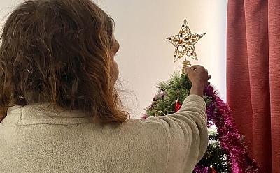 Connie putting star decoration on a Christmas tree
