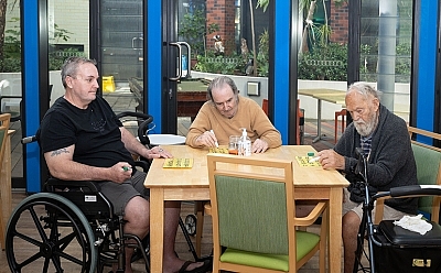 Three people sitting around a table playing bingo.