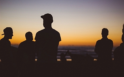 Silhouettes of people by the beach at sunset.