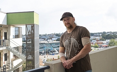 A man standing on a tall balcony with a city view.
