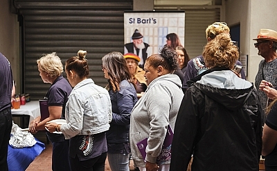A group of people standing in line with a St Bart's banner behind them.